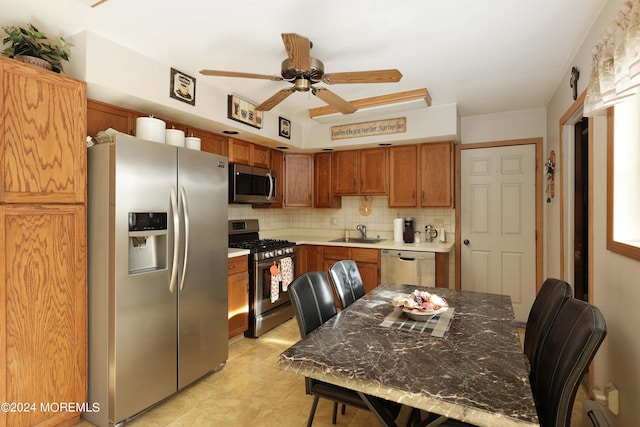 kitchen with appliances with stainless steel finishes, ceiling fan, tasteful backsplash, and sink