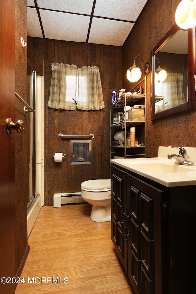 bathroom featuring toilet, walk in shower, wood walls, a baseboard radiator, and vanity