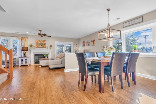 dining room with ceiling fan with notable chandelier and light hardwood / wood-style flooring