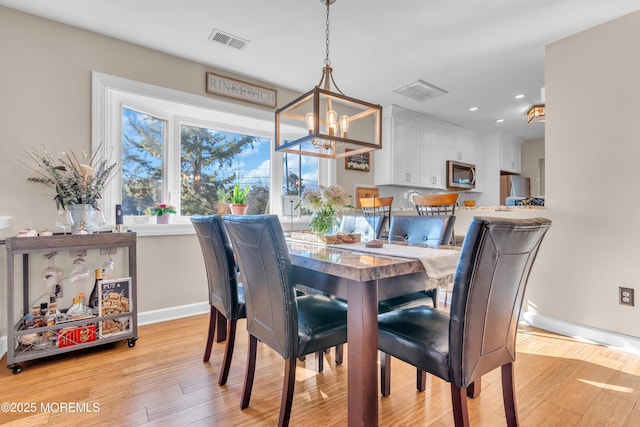 dining space with light wood-type flooring and a notable chandelier