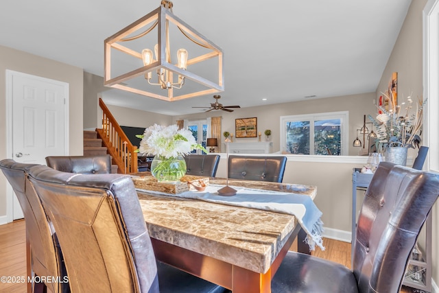 dining room with ceiling fan with notable chandelier and light wood-type flooring