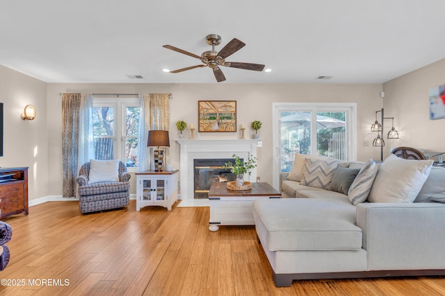 living room featuring ceiling fan, plenty of natural light, and light wood-type flooring