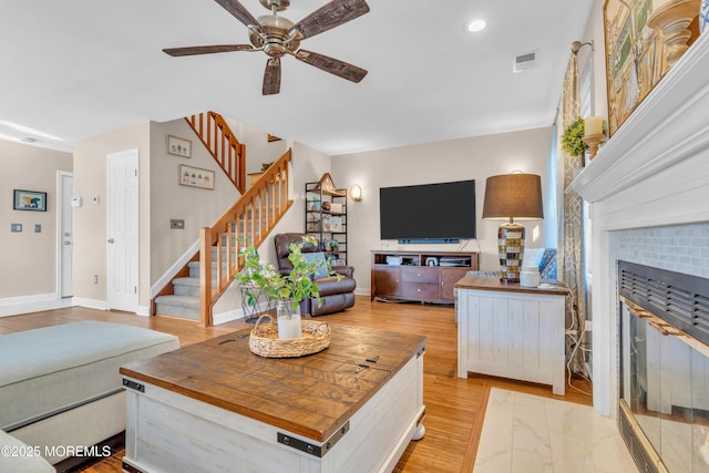 living room featuring a brick fireplace and ceiling fan