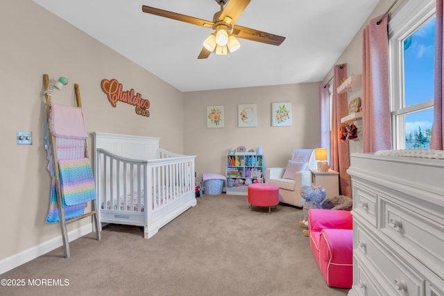 bedroom featuring ceiling fan, light colored carpet, and a crib