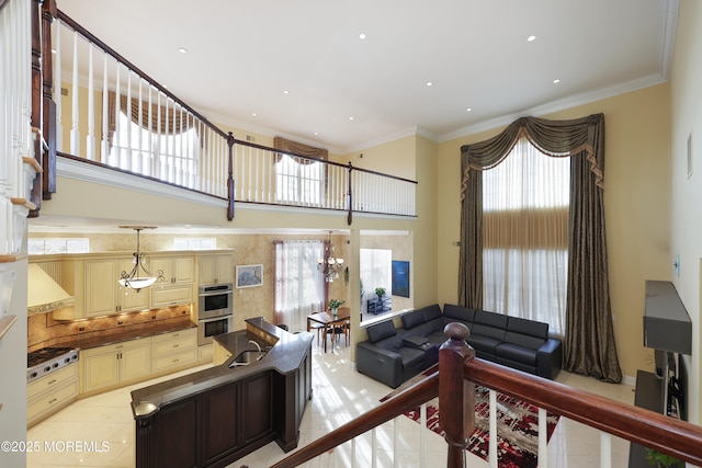 living room featuring sink, light tile patterned floors, ornamental molding, and an inviting chandelier