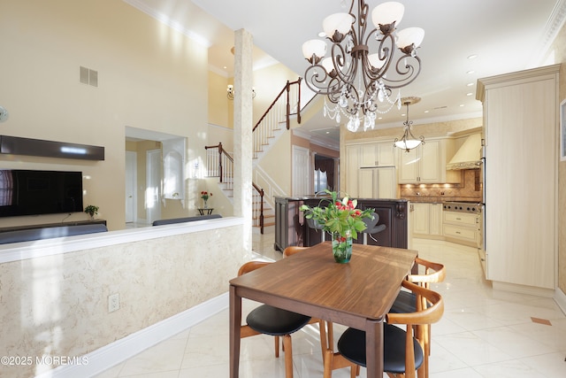 tiled dining room with a notable chandelier, a towering ceiling, and ornamental molding