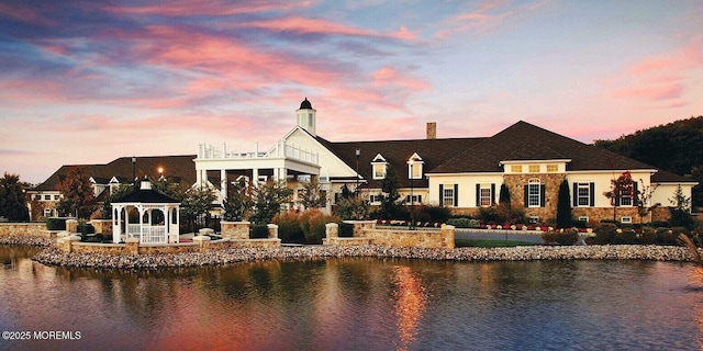 back house at dusk featuring a gazebo and a water view