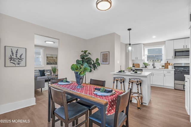 dining space with sink, light wood-type flooring, and a wealth of natural light