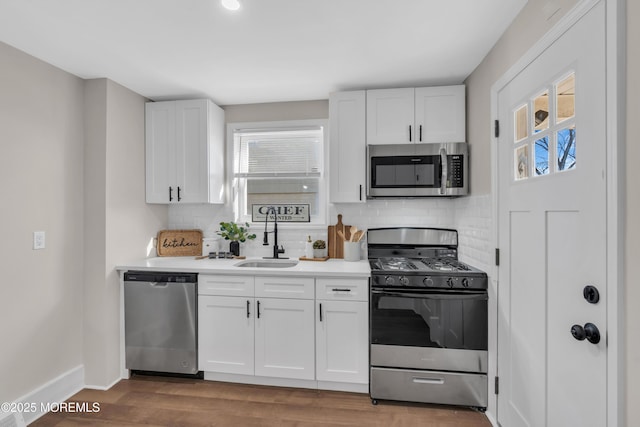 kitchen featuring backsplash, hardwood / wood-style floors, sink, appliances with stainless steel finishes, and white cabinets