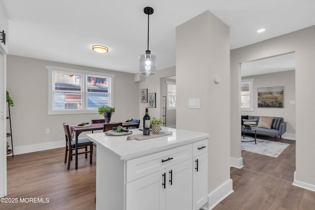 kitchen with a wealth of natural light, light hardwood / wood-style flooring, white cabinets, and hanging light fixtures