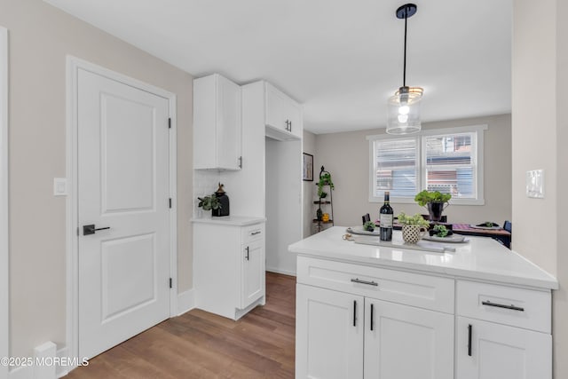 kitchen with light hardwood / wood-style floors, backsplash, pendant lighting, and white cabinets