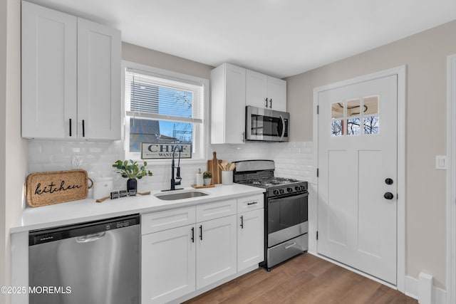 kitchen featuring stainless steel appliances, decorative backsplash, white cabinets, and sink