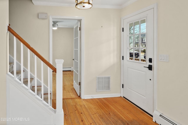 entryway with a baseboard heating unit, ornamental molding, and light wood-type flooring