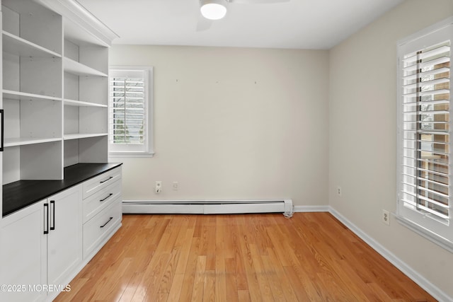 empty room with ceiling fan, a baseboard radiator, and light hardwood / wood-style flooring