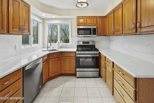 kitchen with stainless steel appliances, backsplash, light stone counters, and sink