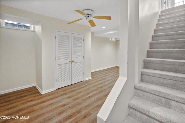 staircase featuring ceiling fan and hardwood / wood-style floors