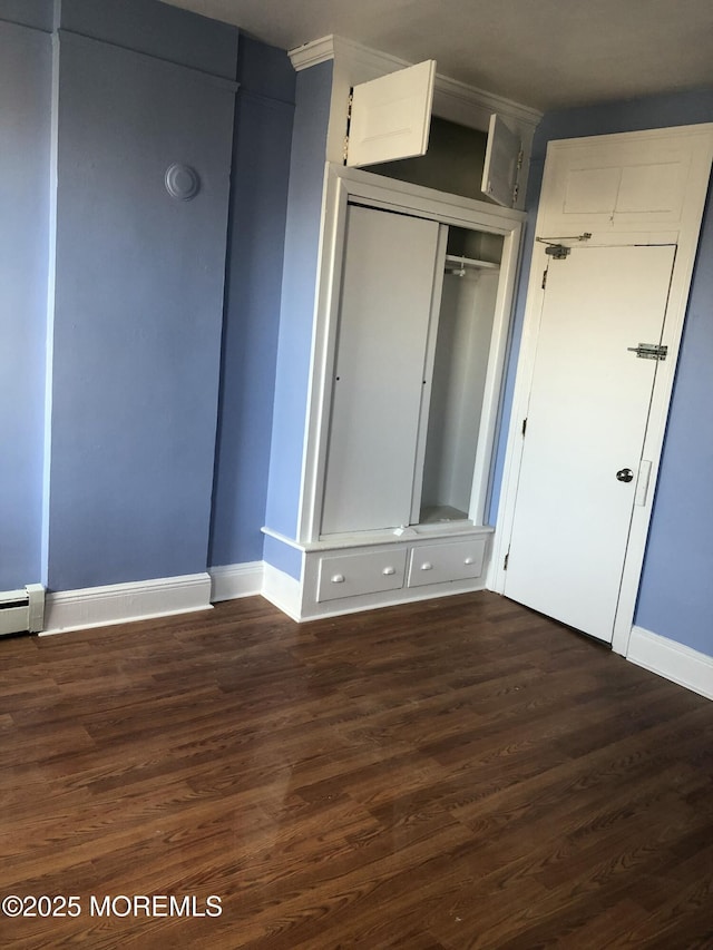 unfurnished bedroom featuring a closet, dark wood-type flooring, and a baseboard radiator