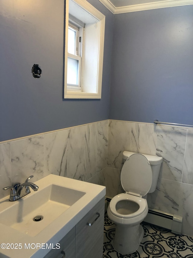 bathroom with toilet, vanity, tile walls, crown molding, and baseboard heating