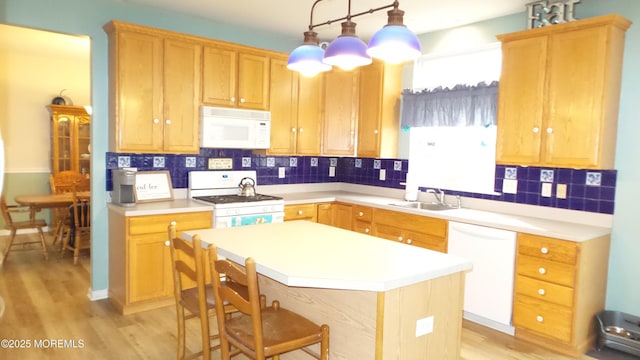 kitchen featuring pendant lighting, white appliances, a center island, sink, and backsplash