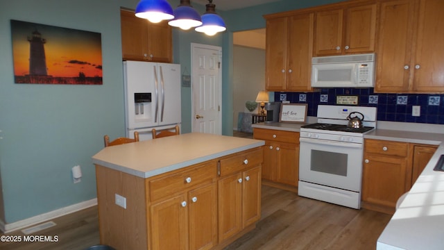 kitchen with white appliances, a center island, tasteful backsplash, hanging light fixtures, and light wood-type flooring