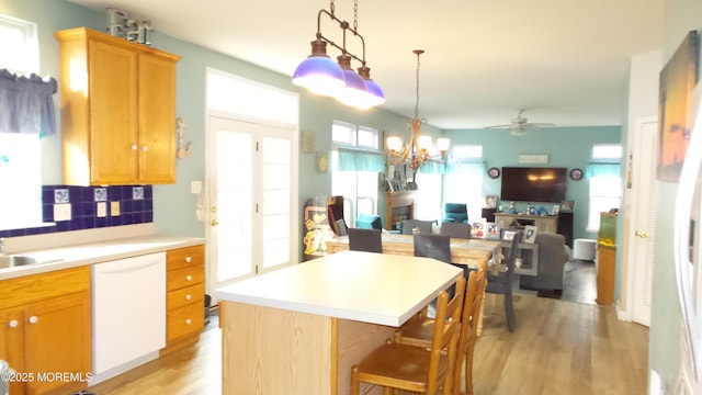 kitchen featuring decorative backsplash, white dishwasher, ceiling fan with notable chandelier, light hardwood / wood-style flooring, and a center island