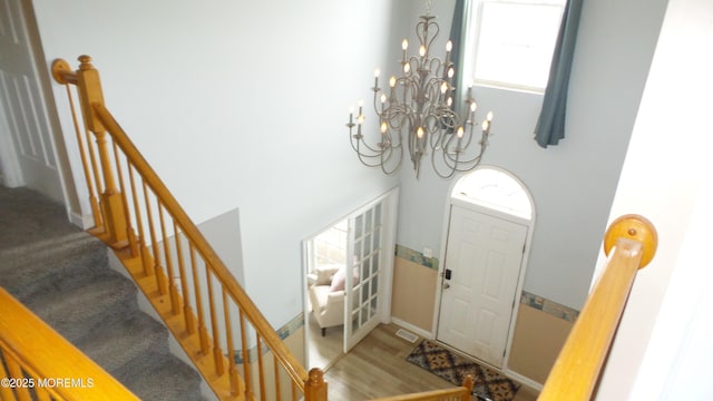 entryway with a towering ceiling, a notable chandelier, and hardwood / wood-style flooring