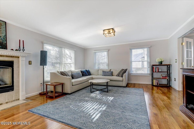 living room with crown molding, a fireplace, baseboards, and wood finished floors