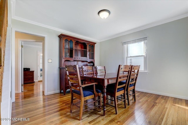 dining area featuring baseboards, ornamental molding, and wood finished floors