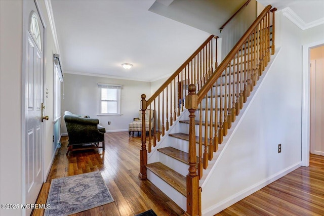 stairway with baseboards, crown molding, and wood finished floors