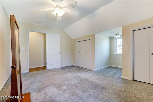 unfurnished bedroom with baseboards, ceiling fan, two closets, and light colored carpet