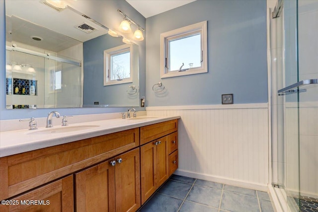 bathroom with double vanity, a wainscoted wall, a sink, and tile patterned floors