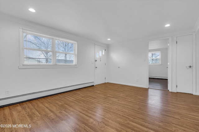 empty room with crown molding, light hardwood / wood-style flooring, and a baseboard radiator