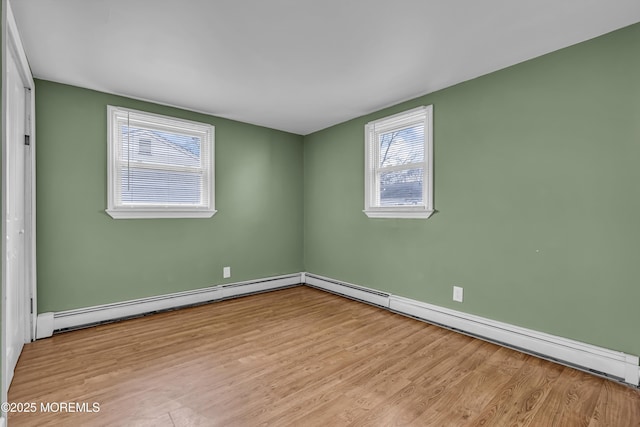 spare room with a baseboard heating unit and light hardwood / wood-style floors