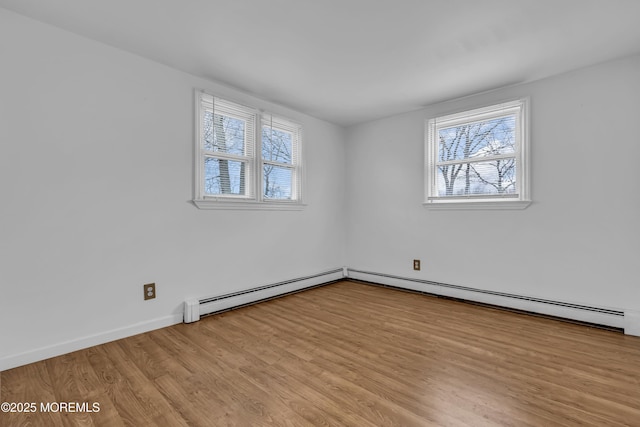 empty room with baseboard heating and light hardwood / wood-style floors