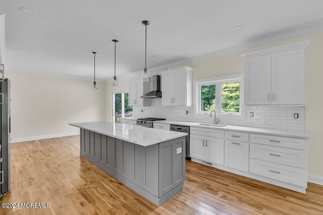 kitchen featuring pendant lighting, a center island, white cabinetry, appliances with stainless steel finishes, and wall chimney exhaust hood