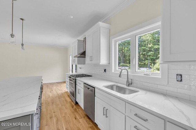 kitchen with light stone countertops, white cabinets, appliances with stainless steel finishes, decorative light fixtures, and sink