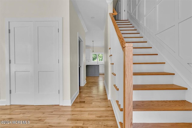 stairway featuring hardwood / wood-style floors and crown molding