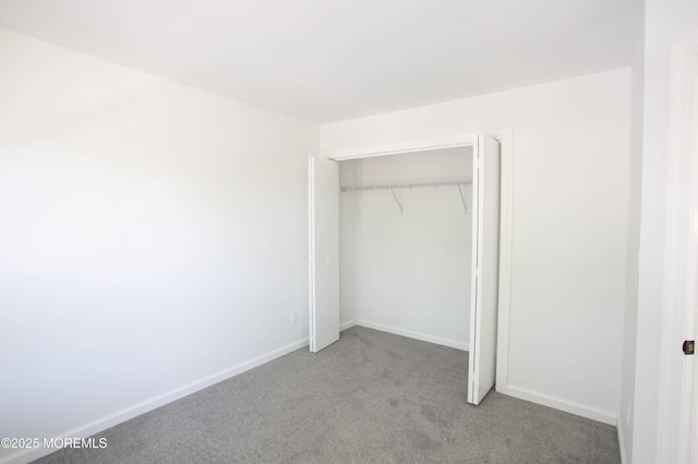 unfurnished bedroom with light colored carpet and a closet