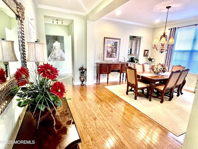 dining area featuring an inviting chandelier, ornamental molding, and wood-type flooring