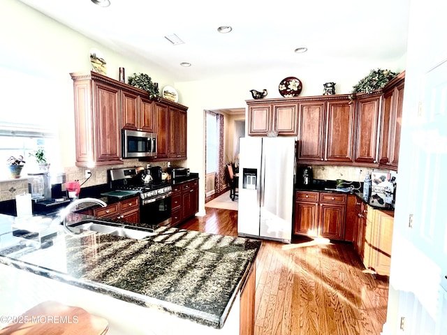 kitchen featuring appliances with stainless steel finishes, tasteful backsplash, light hardwood / wood-style floors, sink, and kitchen peninsula