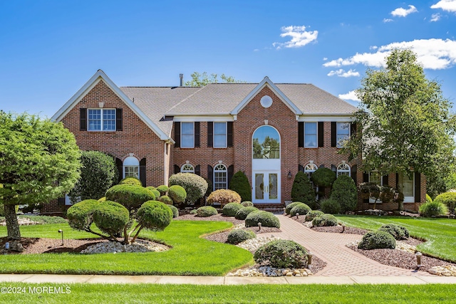 colonial home with a front lawn and french doors