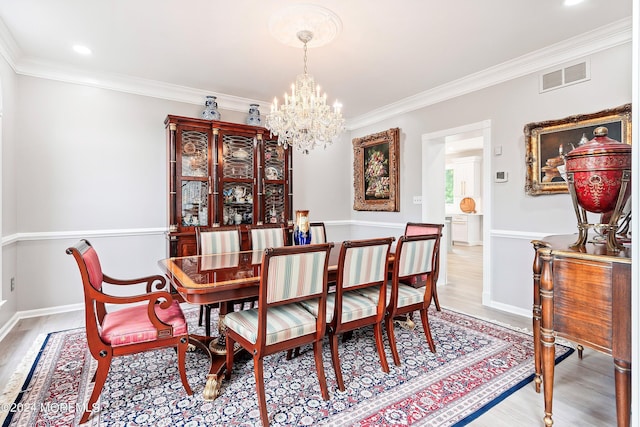 dining area featuring light hardwood / wood-style floors, ornamental molding, and a chandelier