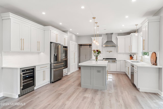 kitchen featuring white cabinetry, beverage cooler, hanging light fixtures, a kitchen island, and wall chimney exhaust hood