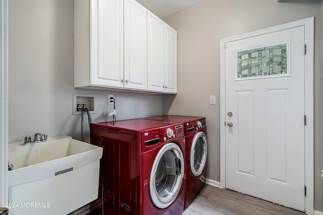 clothes washing area featuring cabinets, washer and dryer, light hardwood / wood-style flooring, and sink