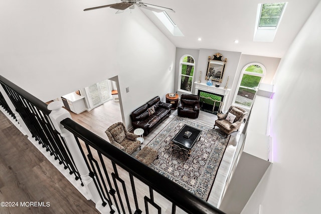 living room featuring high vaulted ceiling, a skylight, ceiling fan, and hardwood / wood-style flooring