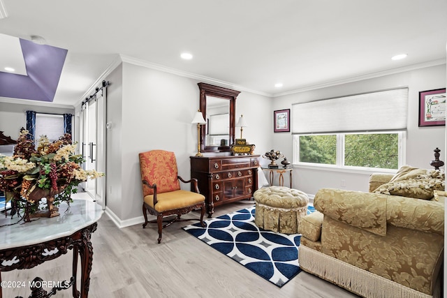 living area featuring light wood-type flooring, ornamental molding, and a barn door