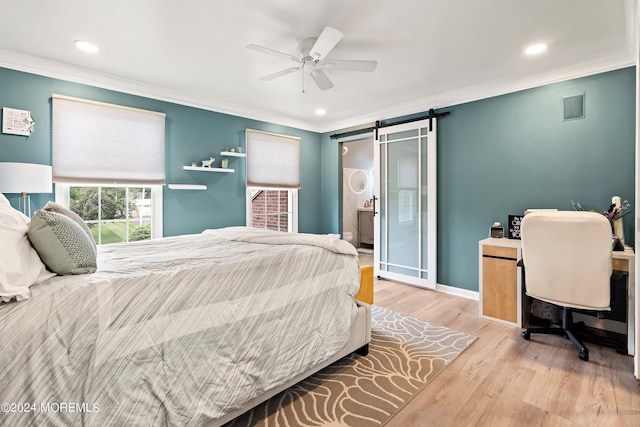 bedroom featuring ceiling fan, light hardwood / wood-style floors, a barn door, and crown molding