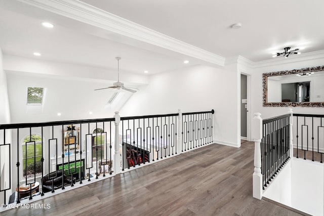 corridor with lofted ceiling with skylight, crown molding, and hardwood / wood-style floors