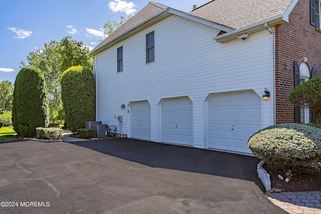 view of property exterior with a garage and central AC