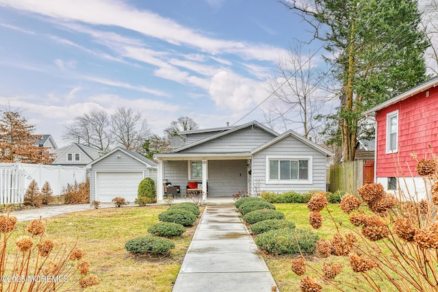 bungalow-style house featuring covered porch, an outdoor structure, a garage, and a front lawn